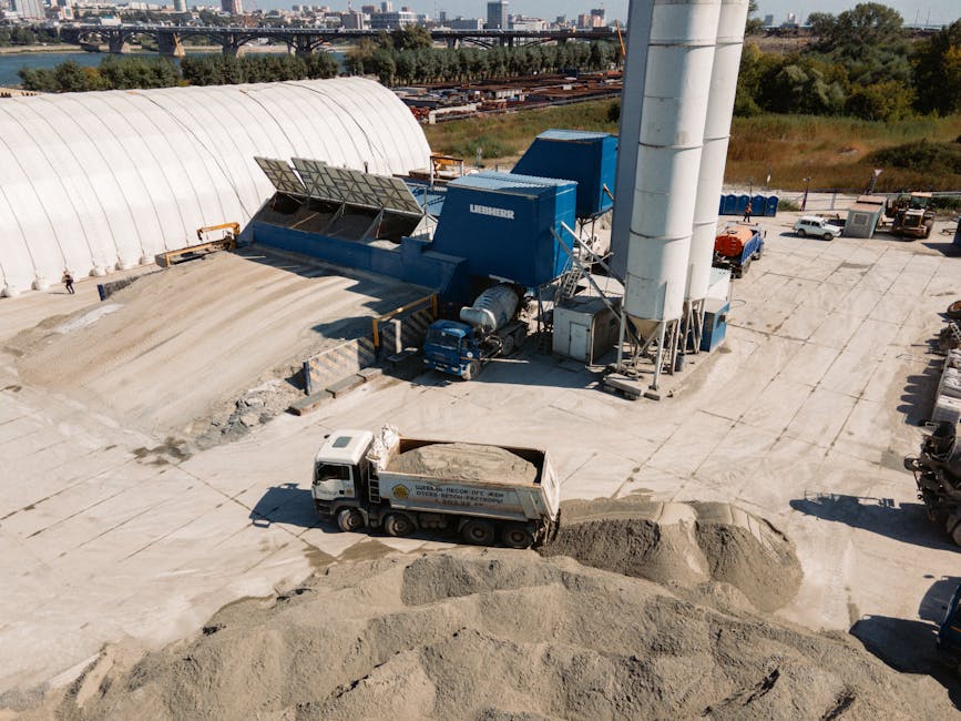 Pracownicy budowlani wyrównujący warstwę suchego betonu pod nawierzchnię przemysłową na dużej inwestycji logistycznej
